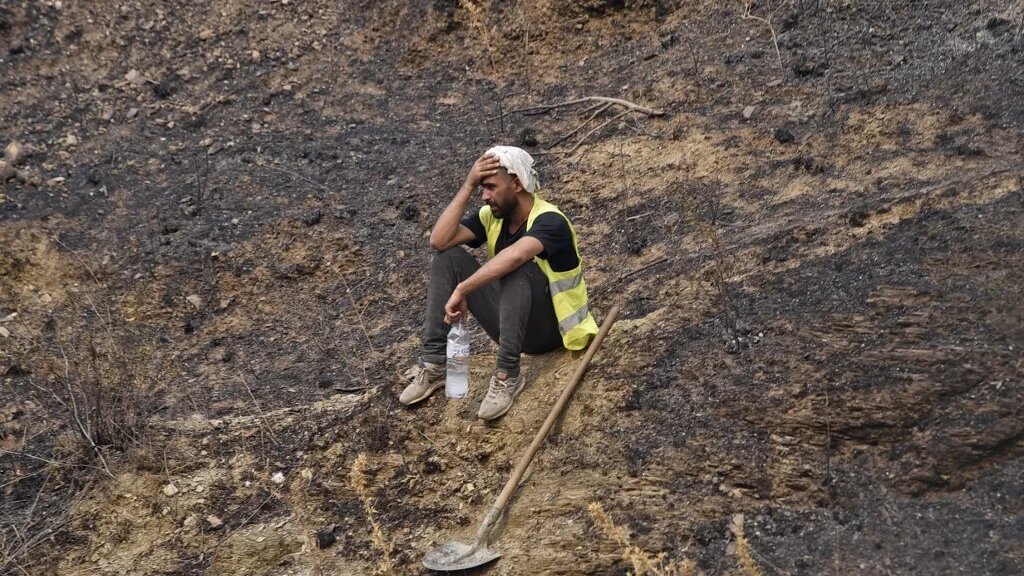 Un volontaire se repose après avoir combattu le feu, près de Tizi Ouzou, en Kabylie, le 12 août 2021 (AFP/Ryad Kramdi)