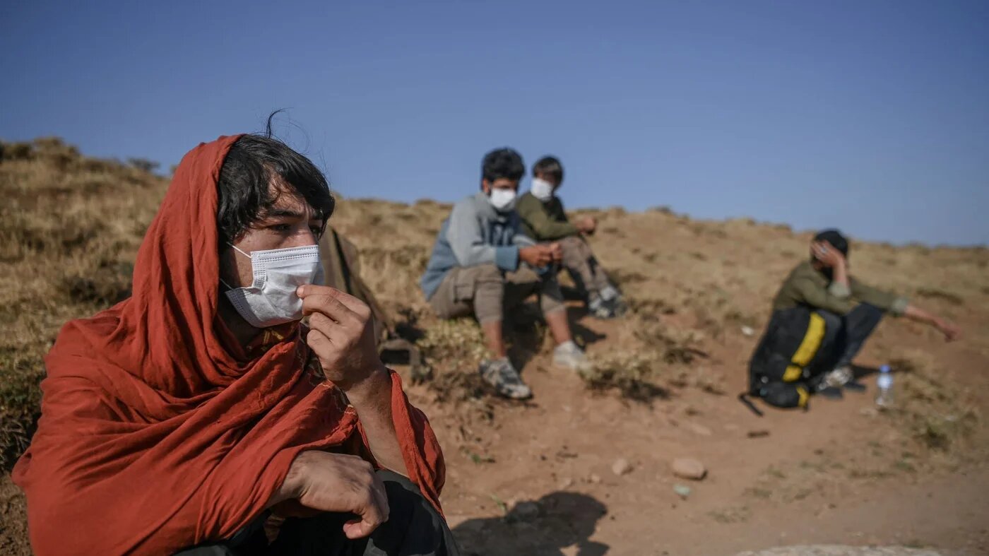 Afghan migrants rest while waiting for transport by smugglers after crossing the Iran-Turkish border in Tatvan, on the western shores of Lake Van, eastern Turkey, on 15 August 2021 (AFP)
