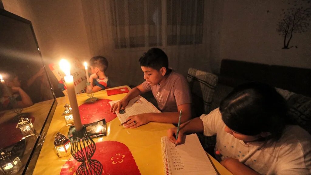 Des enfants, à Tripoli, font leurs devoirs à la lumière des bougies, le 26 août 2021 (AFP/Mahmud Turkia) 