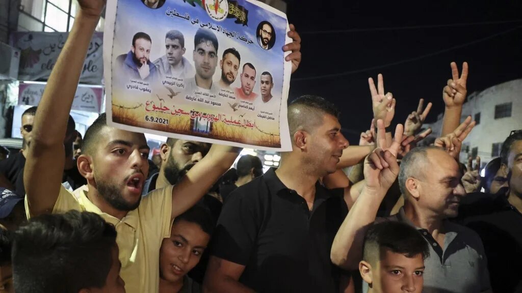 A Palestinian man shows a poster of the six Palestinians who escaped from an Israeli prison 