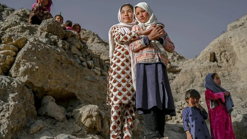 Des enfants de l’ethnie Hazara se tiennent sur une falaise creusée de grottes où les gens vivent encore comme il y a des siècles à Bamiyan, en Afghanistan, le 3 octobre 2021 (AFP/Bulent Kilic)
