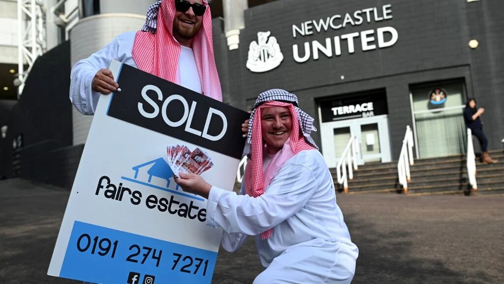 Des supporteurs de Newcastle, vêtus comme des Saoudiens, fêtent la vente de leur club à l’Arabie saoudite (AFP/Oli Scarff)