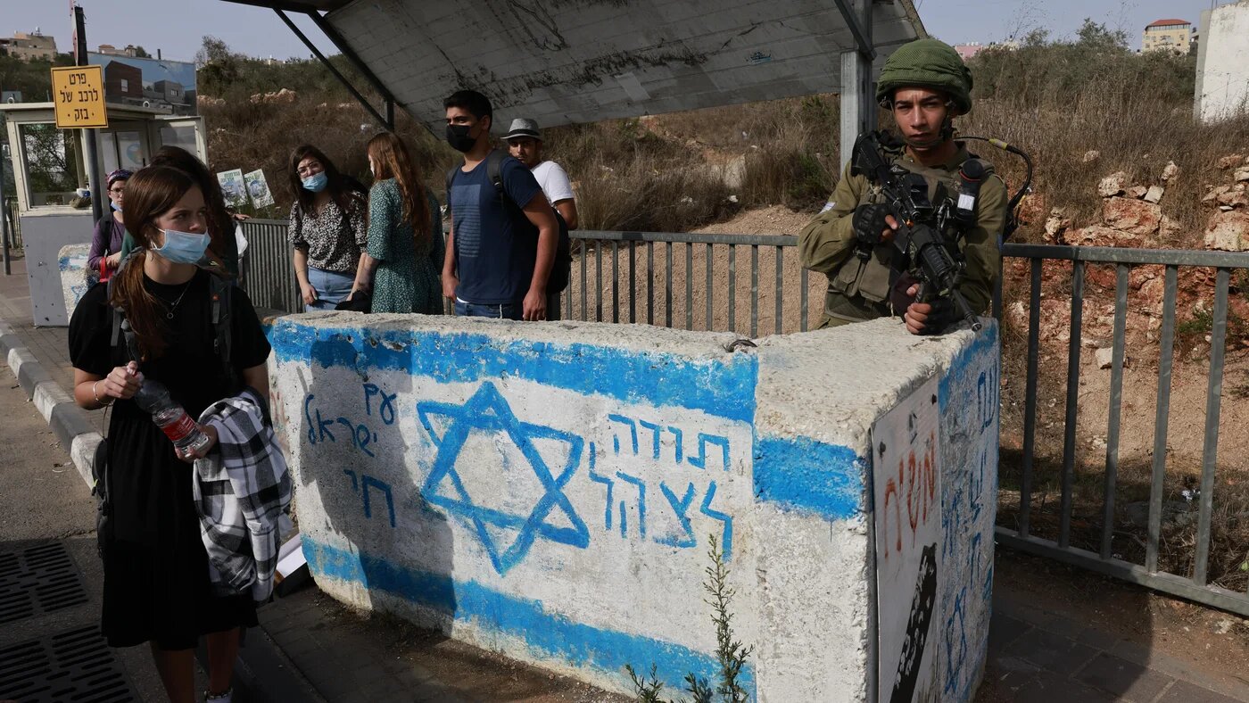 An Israeli soldier on guard at a bus station near the Jewish settlement of Ariel in the occupied West Bank on 14 October 2021 (AFP)