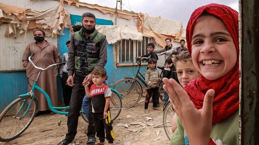 Une fille regarde flanquée d'enfants à bicyclette dans le camp de réfugiés de Zaatari, à quelque 80 kilomètres (50 miles) au nord de la capitale jordanienne, le 19 novembre 2021. Khalil MAZRAAWI / AFP