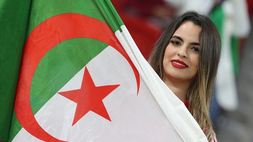Une Algérienne secoue le drapeau de son pays, lors de la demi-finale de la Coupe arabe entre l’Algérie et le Qatar, le 15 décembre 2021 (AFP/Karim Jaafar)