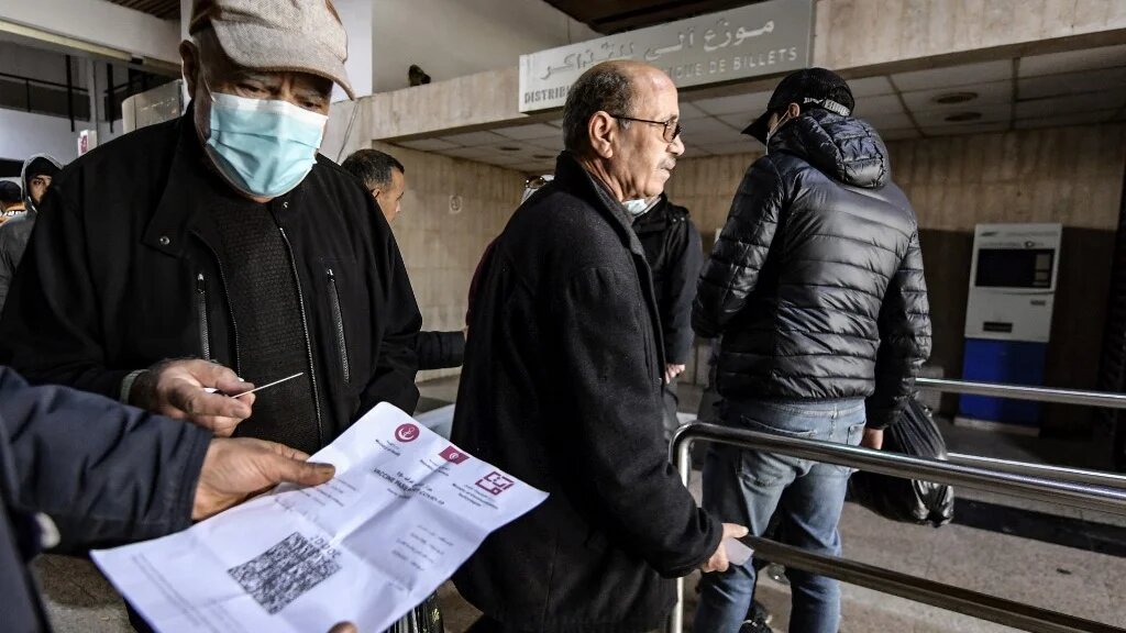 Un employé des transports publics tunisiens contrôle le pass vaccinal d’un passager à l’entrée d’une gare de la capitale Tunis, le 22 décembre 2021 (AFP/Fethi Belaid)