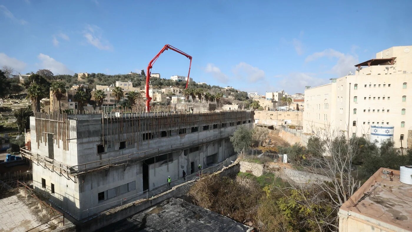 Builders work on new constructions in a settlement zone in the occupied West Bank's Hebron (AFP)