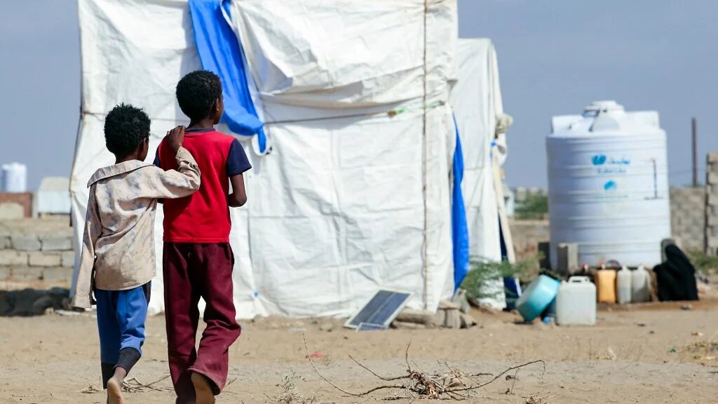 Children walk in front of tents at a camp for displaced Yemenis in the village of Hays, near the western province of Hodeida, on 5 February 2022 