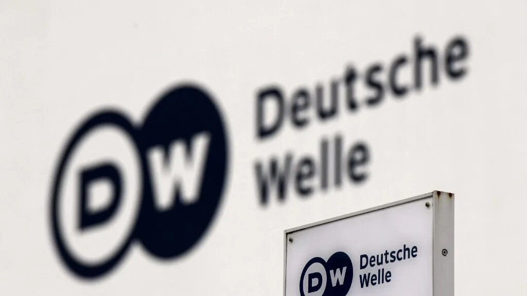 A picture shows a the logo of German international broadcaster Deutsche Welle (DW) on a board and on a wall at their head office in Bonn, Germany, on 8 February 2022 (AFP)