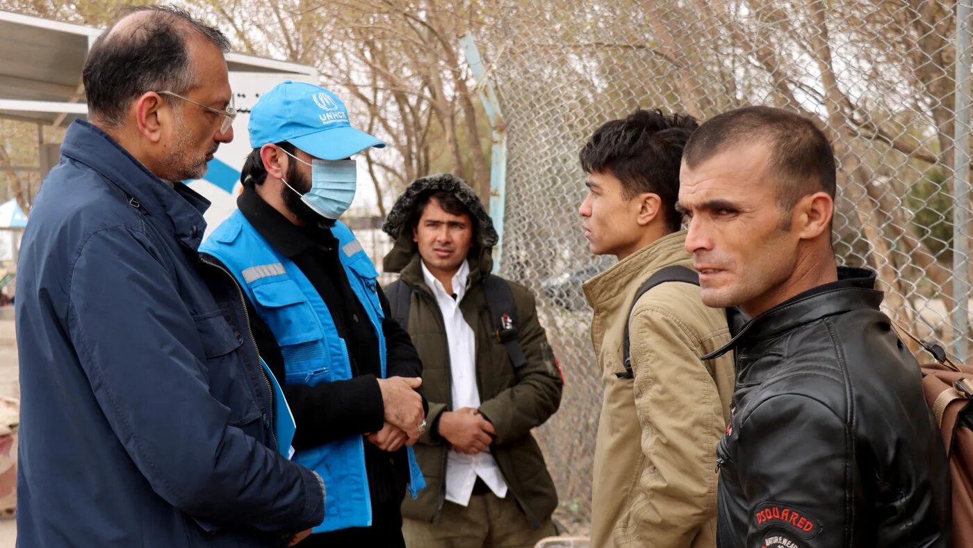 Arafat Jamal (left), representative of the United Nations High Commissioner for Refugees (UNHCR) in Afghanistan, speaks with Afghan nationals upon their arrival from Iran amid the Middle East war.
