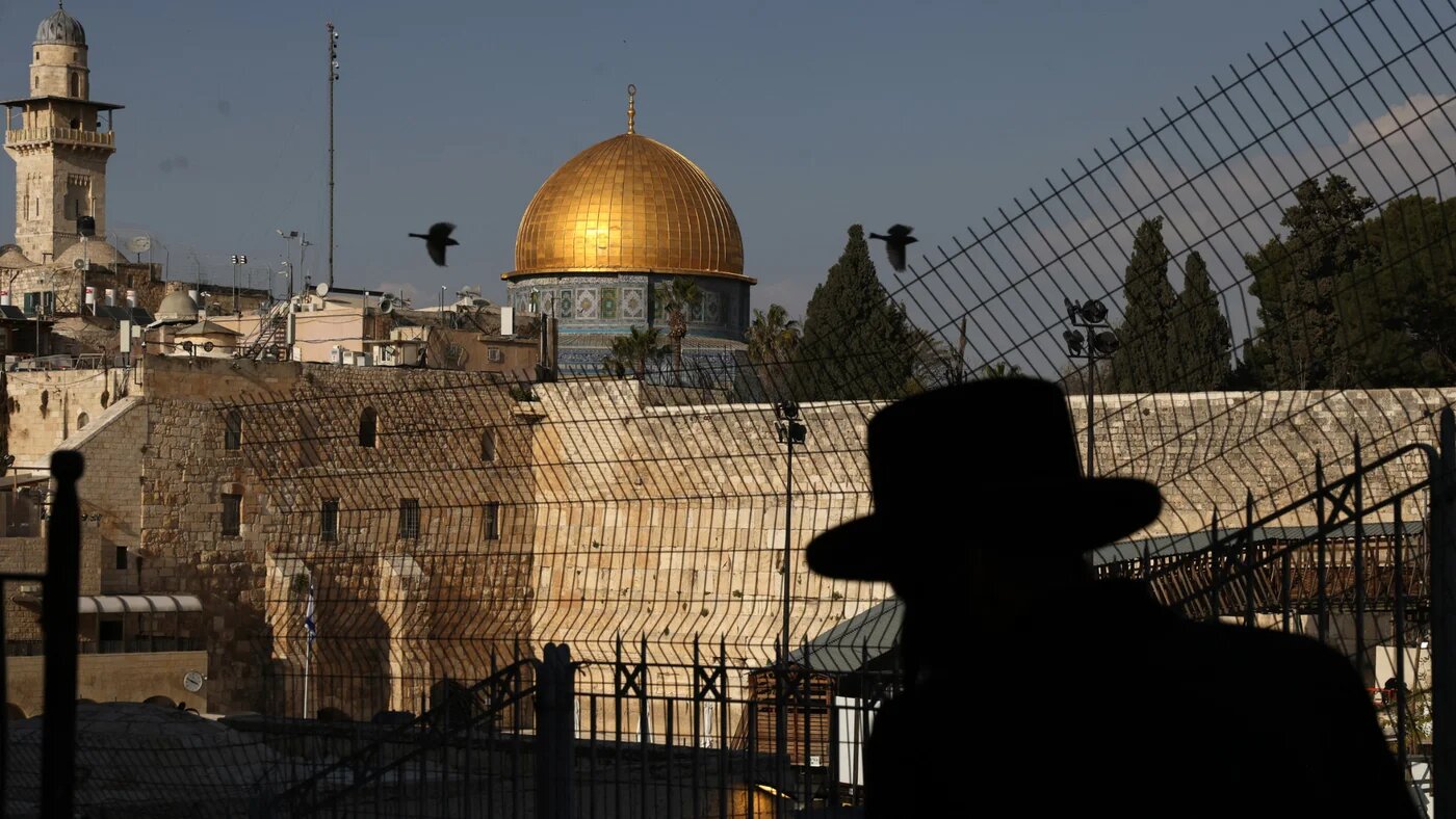 Jews pray outside of the Western Wall, with the al-Aqsa Mosque pictured in the background, in the Old City of Jerusalem on 12 March 2026 (AFP/Hazem Bader)
