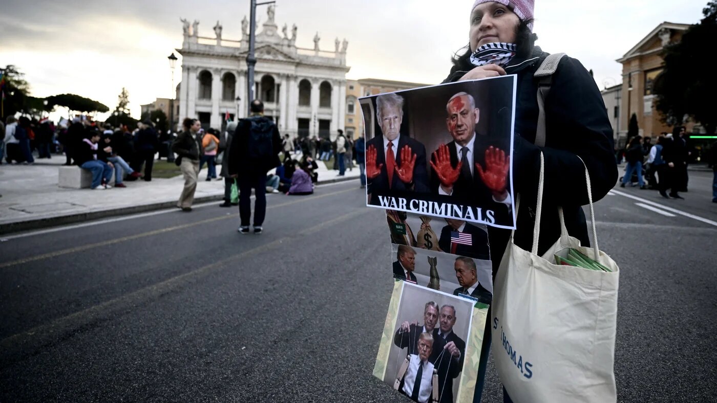 A demonstrator holds a banner depicting US President Donald Trump and Israeli Prime Minister Benjamin Netanyahu during a protest against the US-Israel war on Iran in Rome, Italy, 14 March 2026 (Filippo Monteforte/AFP)