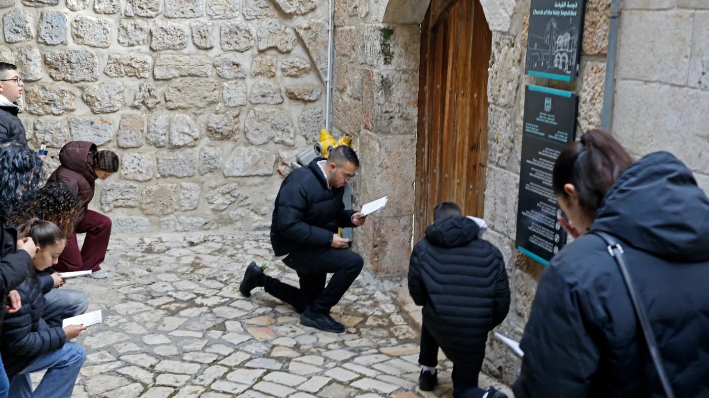 Christian pilgrims pray in front of the closed door of Church of the Holy Sepulchre in the Old City of Jerusalem on 3 April 2026 (Marco Longari/AFP)