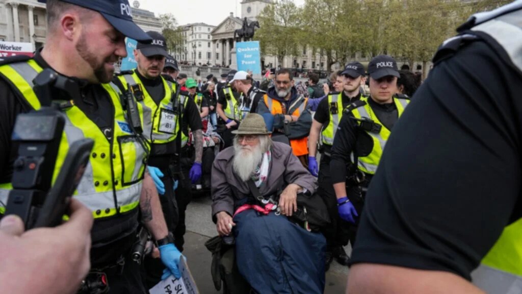 An elderly man in a wheelchair (C) is escorted away by police as protesters gather to call for the lifting of the ban on the Palestine Action group during a demonstration in Trafalgar Square in central London on April 11, 2026. 