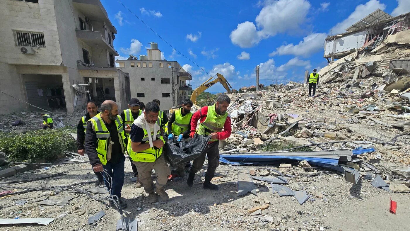 First responders carry a body from the rubble of buildings destroyed in an Israeli strike in Qana, southern Lebanon, on 12 April 2026 (Kawnat Haju/AFP)