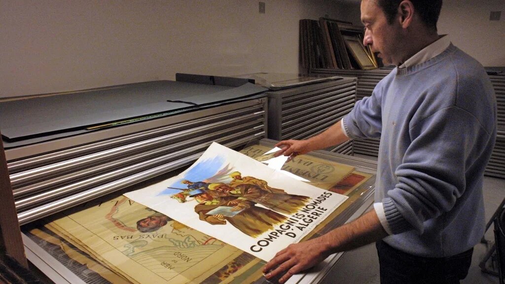 Un homme regarde des affiches datant de la guerre d’Algérie dans une salle du Service historique de l’Armée de terre (SHAT), dans le fort de Vincennes, le 29 octobre 2001 (AFP)