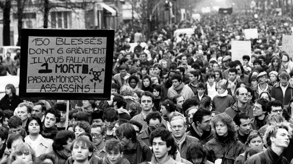 Plusieurs milliers de personnes manifestent silencieusement, à Paris le 6 décembre 1986, de la place de la Sorbonne à l’hôpital Cochin où repose le corps de Malik Oussekine, le jeune étudiant décédé le matin même après avoir été violemment frappé par des policiers (AFP)