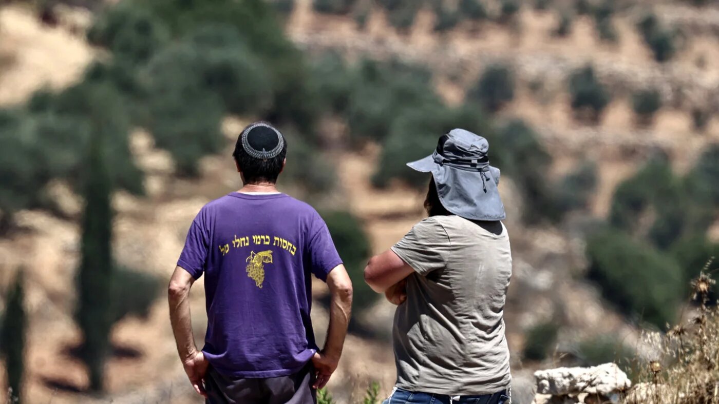 Israeli settlers stand near al-Tireh neighbourhood at the western entrance of the city of Ramallah, in the occupied West Bank, on 14 July 2026 (Zain Jaafar/AFP)