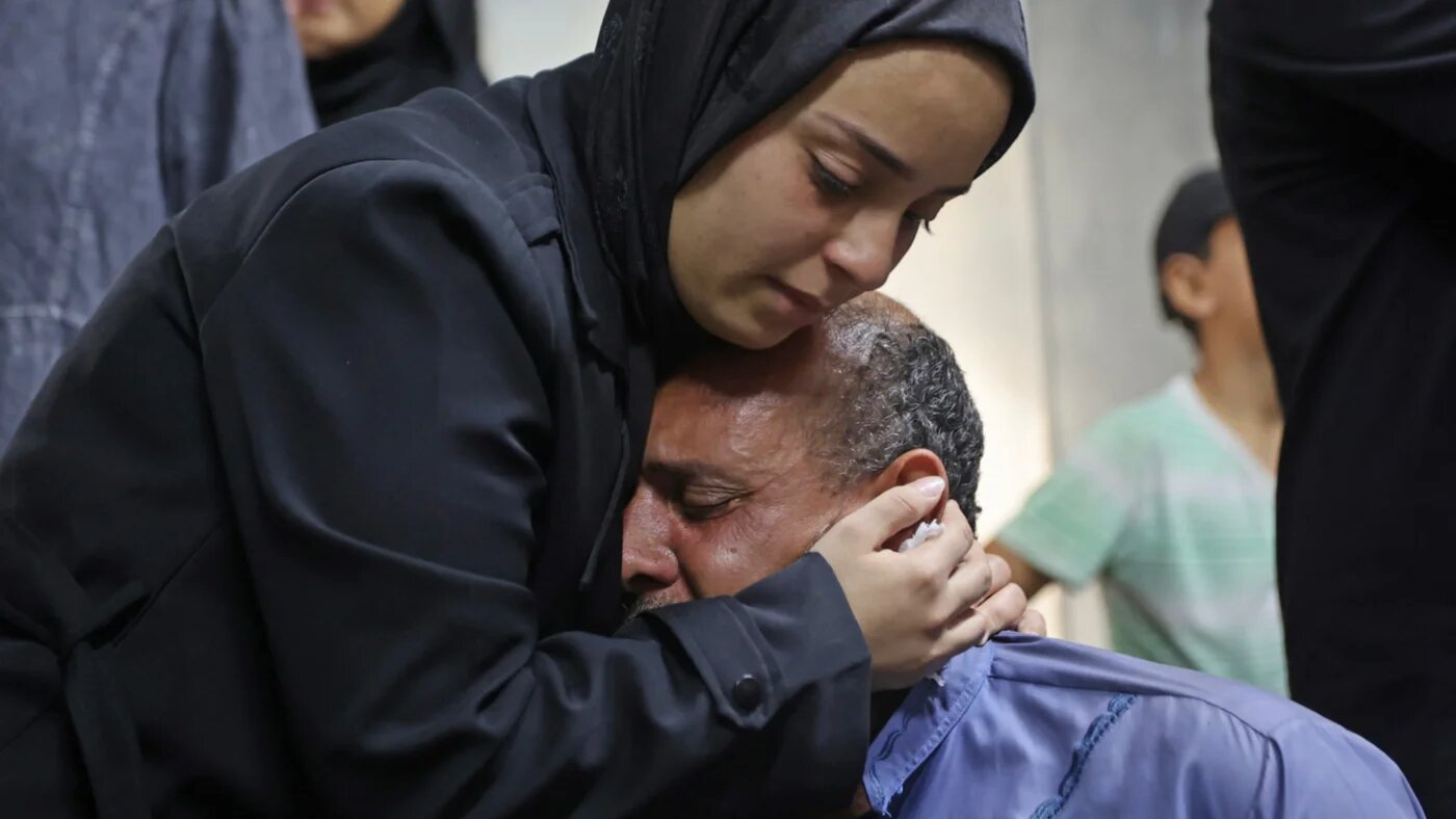 Mourners weep next to the body of one of a Palestinian killed in an Israeli airs trike in Gaza City on 21 July 2026 (Omar al-Qattaa/AFP)