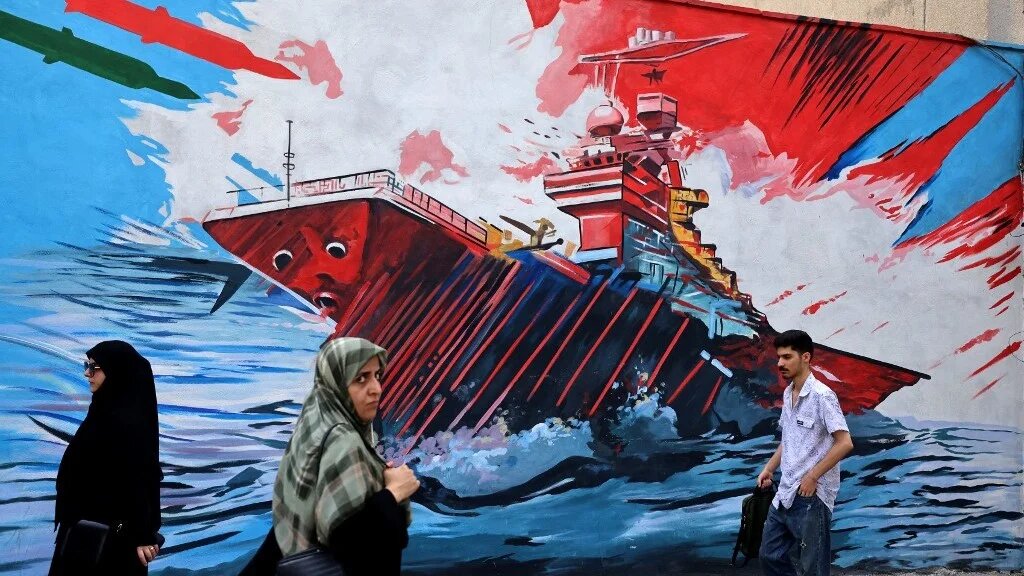 Commuters walk past a wall mural along a street in Tehran on 21 July 2026 (Reuters)
