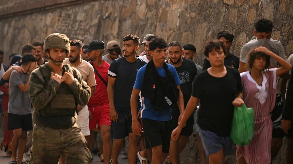 A Spanish soldier escorts a group of migrants on their way back towards the Moroccan border, following their illegal crossing into the Spanish enclave of Ceuta, on August 1, 2026.