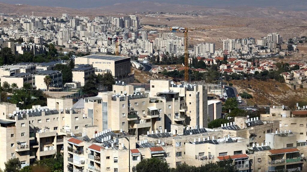 The Israeli settlement of Pisgat Zeev (foreground) in the northern area of east Jerusalem and Israel's controversial barrier separating the Palestinian town Hzma (background) are pictured in the occupied West Bank on August 7, 2026. 