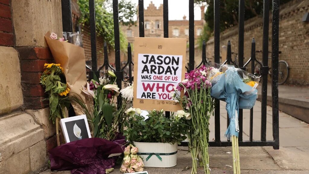 Floral tributes are seen beside the entrance to Jesus College, where the late professor Jason Arday was a fellow at the University of Cambridge in Cambridge, eastern England on 17 August (AFP)