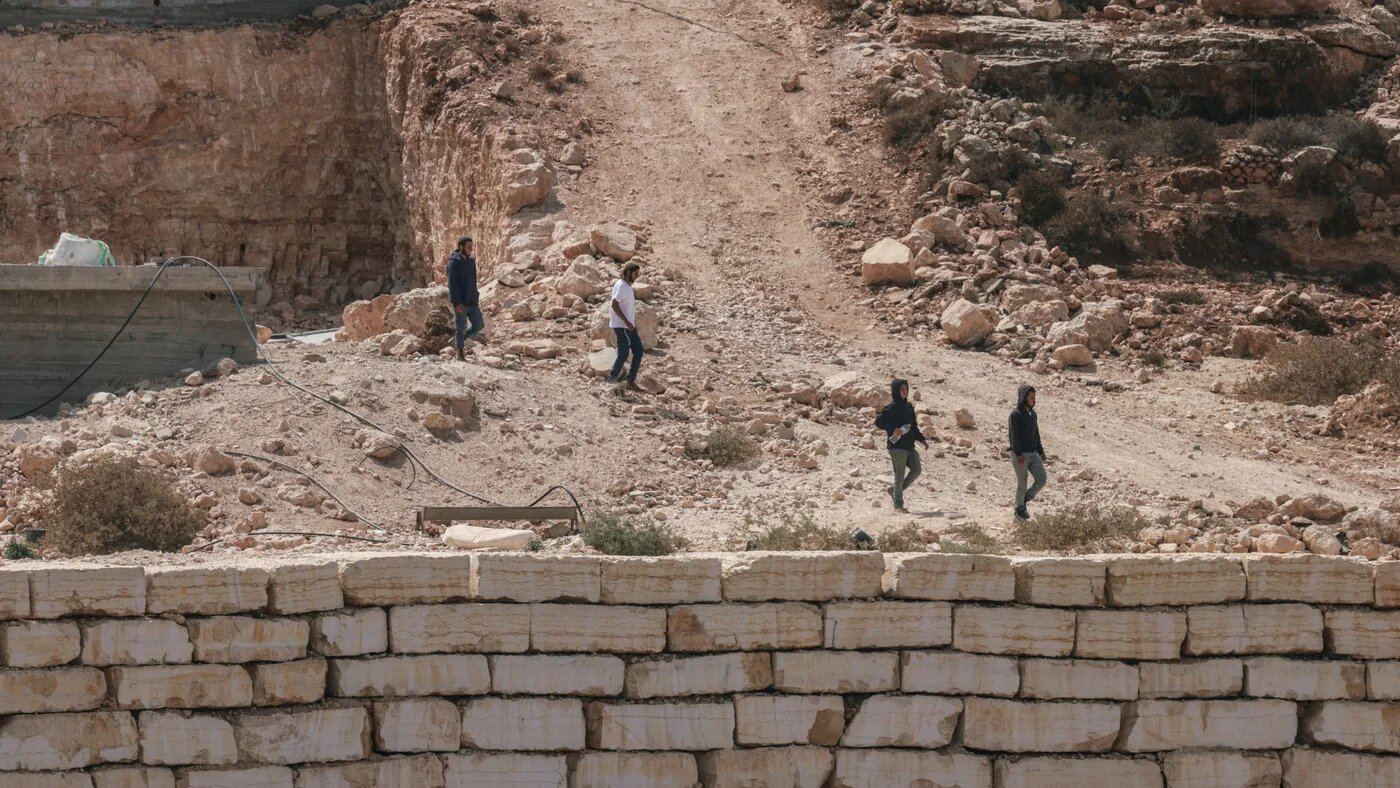 Israeli settlers walk towards a Palestinian home under construction in the village of Qusra, south of Nablus in the occupied West Bank, on 29 August 2026