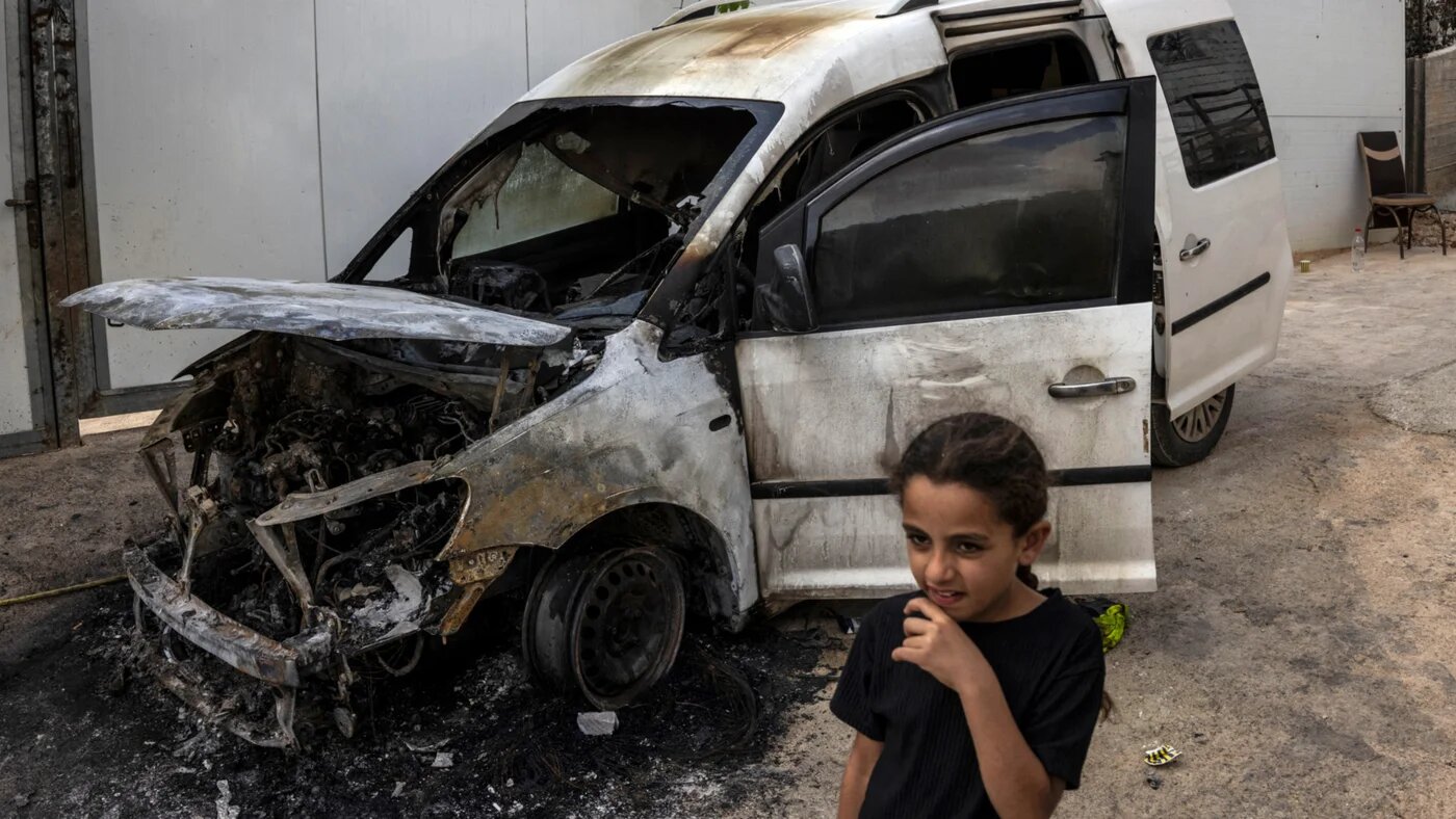 A Palestinian girl walks past a vehicle that was burned by Israeli settlers the previous night, in Aqraba in the occupied West Bank on 6 October 2026 (John Wessels/AFP)