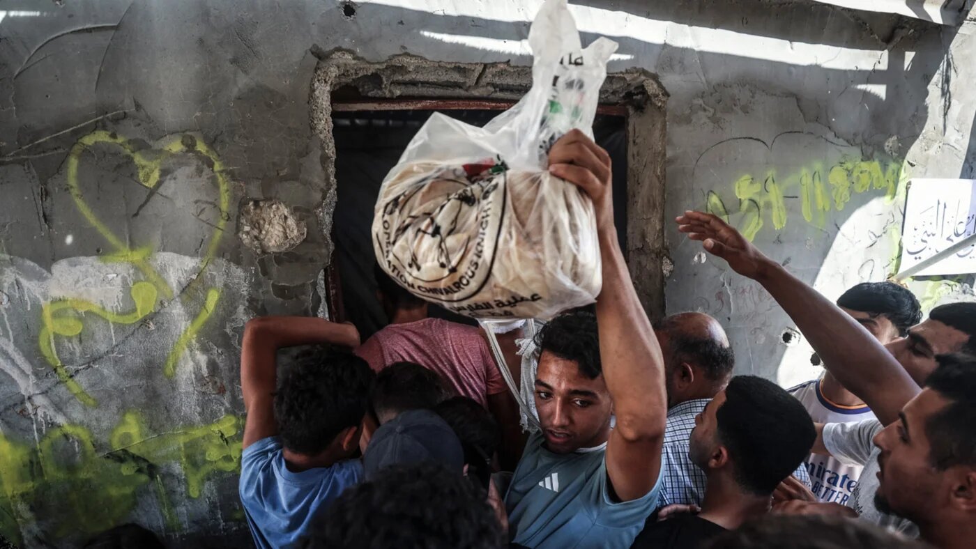 A man carries a bag of bread through a crowd at a bakery in Al-Bureij in the central Gaza Strip on 22 October 2026 (Eyad Baba/AFP)