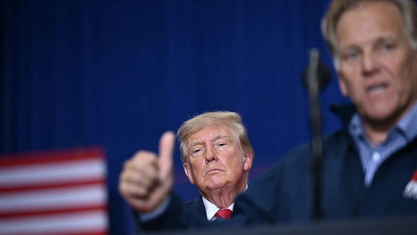 US President Donald Trump listens to Mike Rogers, the Republican candidate for the US Senate in Michigan who is running against Abdul El-Sayed, at a campaign rally in Port Huron on 25 October 2026 (Brendan Smialowski/AFP)