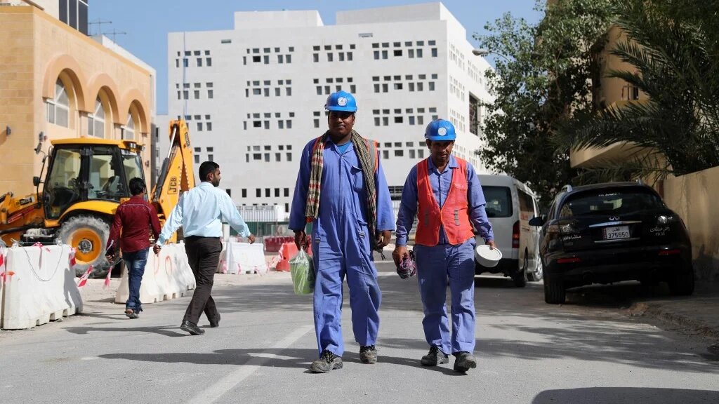 Migrant workers are seen walking next to a construction site in the Qatari capital Doha on 6 December 2016 (AFP)