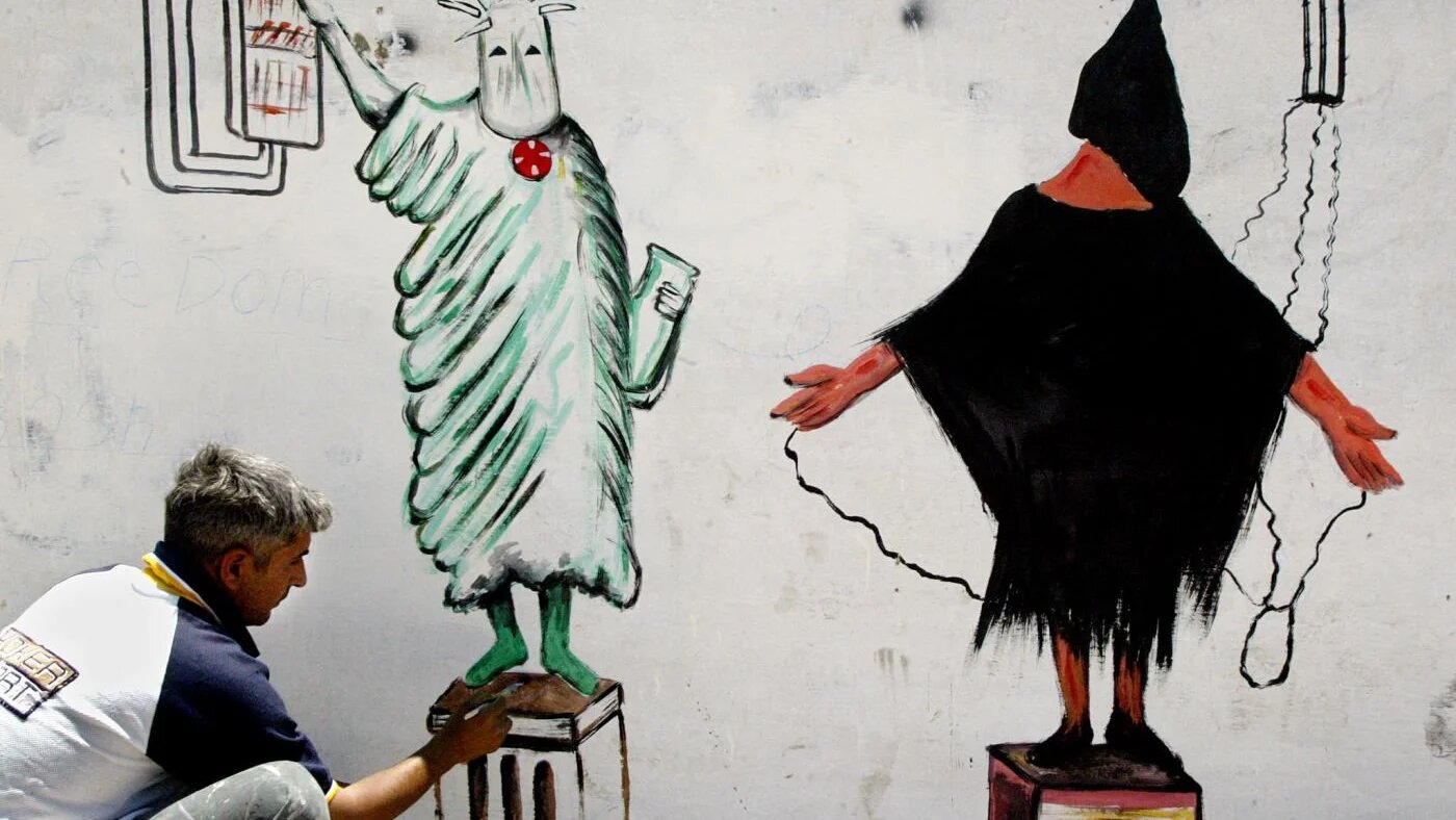 Un artiste irakien peint une fresque d’après la statue de la Liberté et une photo très relayée d’un détenu maltraité à la prison d’Abou Ghraib, à Bagdad en Irak, le 23 mai 2004 (AFP)