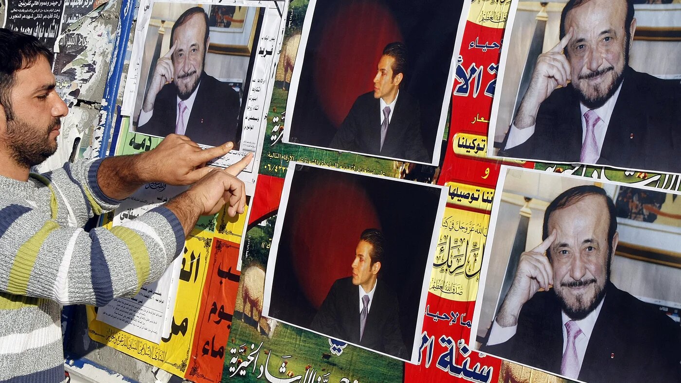 Archive image: A member of the Alawite community pastes posters of Syrian opposition leader Rifaat al-Assad (R) and his son Ribal on a wall in the northern Lebanese city of Tripoli, 06 December 2007
