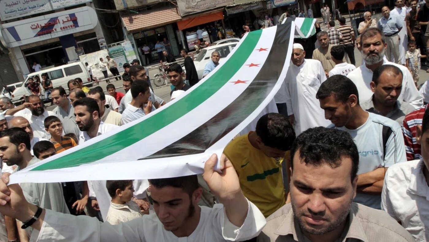 Des Palestiniens portant un drapeau de l’opposition syrienne manifestent contre le président syrien Bachar al-Assad et en soutien aux civils syriens dans le camp de réfugiés de Nuseirat (bande de Gaza), le 22 juin 2012 (AFP)