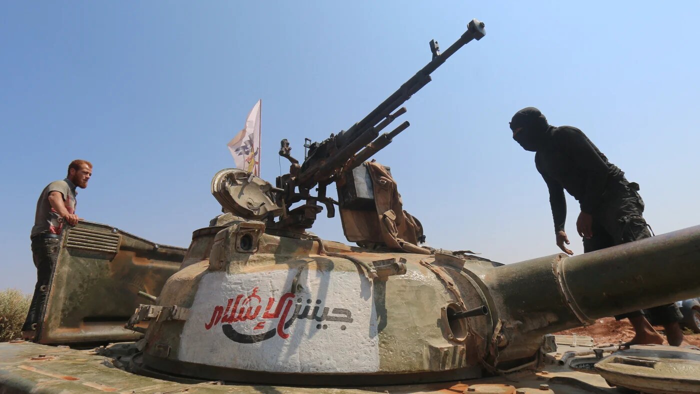 Rebel forces from Jaish al-Islam (Army of Islam) stand on a tank as they hold a position on August 24, 2015 near the frontline in the al-Zahra area, on the northwestern outskirts of Aleppo (AFP)