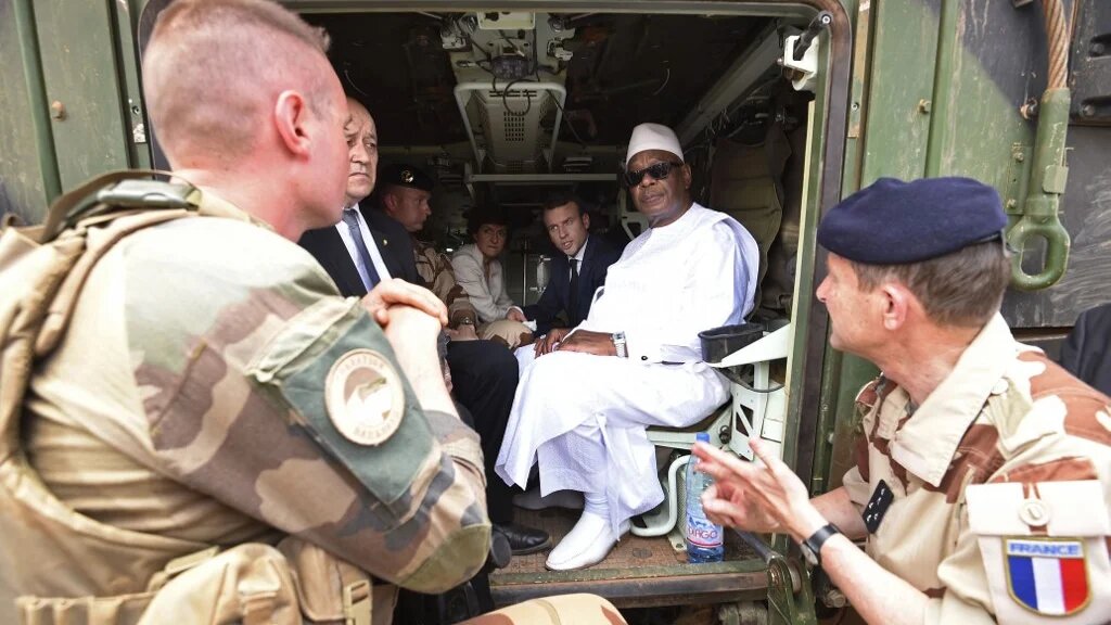 Le président français Emmanuel Macron et le ministre français des Affaires étrangères Jean-Yves Le Drian discutent avec le président malien Ibrahim Boubacar Keïta à l’intérieur d’un véhicule militaire alors qu’ils visitent les troupes de l’opération Barkhane, dans la région africaine du Sahel à Gao, dans le nord du Mali, le 19 mai 2017 (AFP)