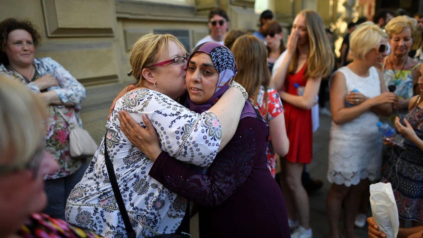 A Muslim woman who attends Didsbury Mosque hugs another lady as she are her family hand out biscuits to members of the public in central Manchester, northwest England on May 26, 2017, as a gesture of solidarity (AFP)