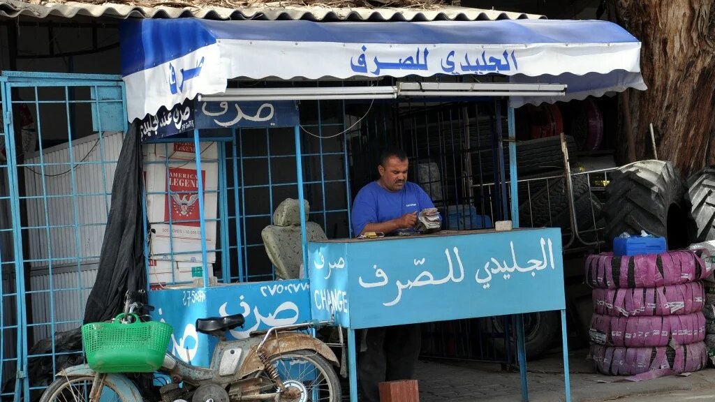 Un épicier tunisien gère son propre service de change au souk de Ras Jedir, à la frontière avec la Libye (AFP)