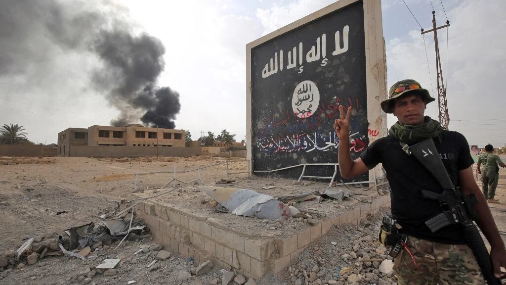 Un combattant du Hachd al-Chaabi devant le drapeau du groupe État islamique à al-Qaim, à l’ouest de l’Irak, le 3 novembre 2017 (AFP/Ahmad al-Rubaye)