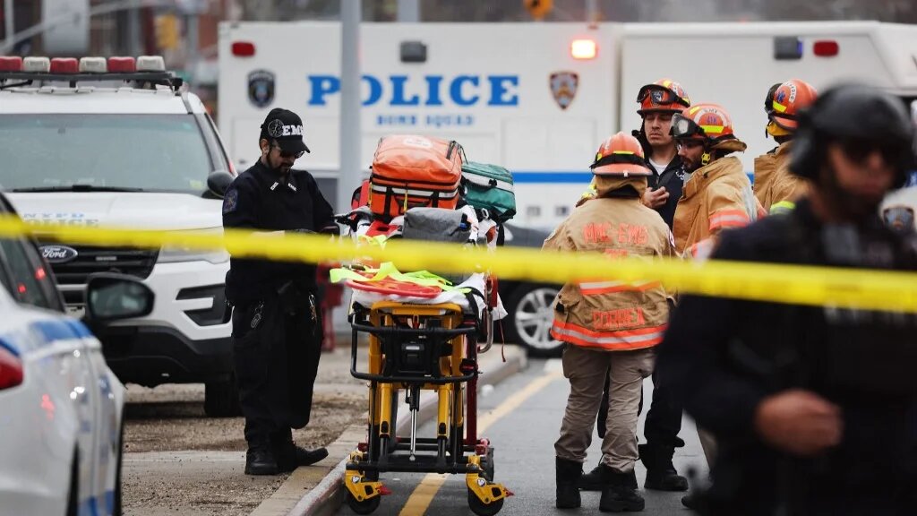 Police and emergency responders gather at the site of a reported shooting of multiple people outside a Brooklyn subway station 12 April (AFP)