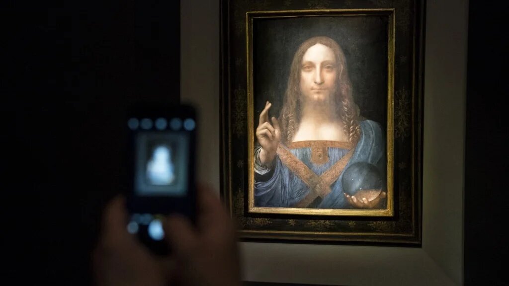 Un visiteur prend des photos du Salvator Mundi qui doit être vendu aux enchères chez Christie’s à New York, le 15 novembre 2017 (AFP/photo d’archives)