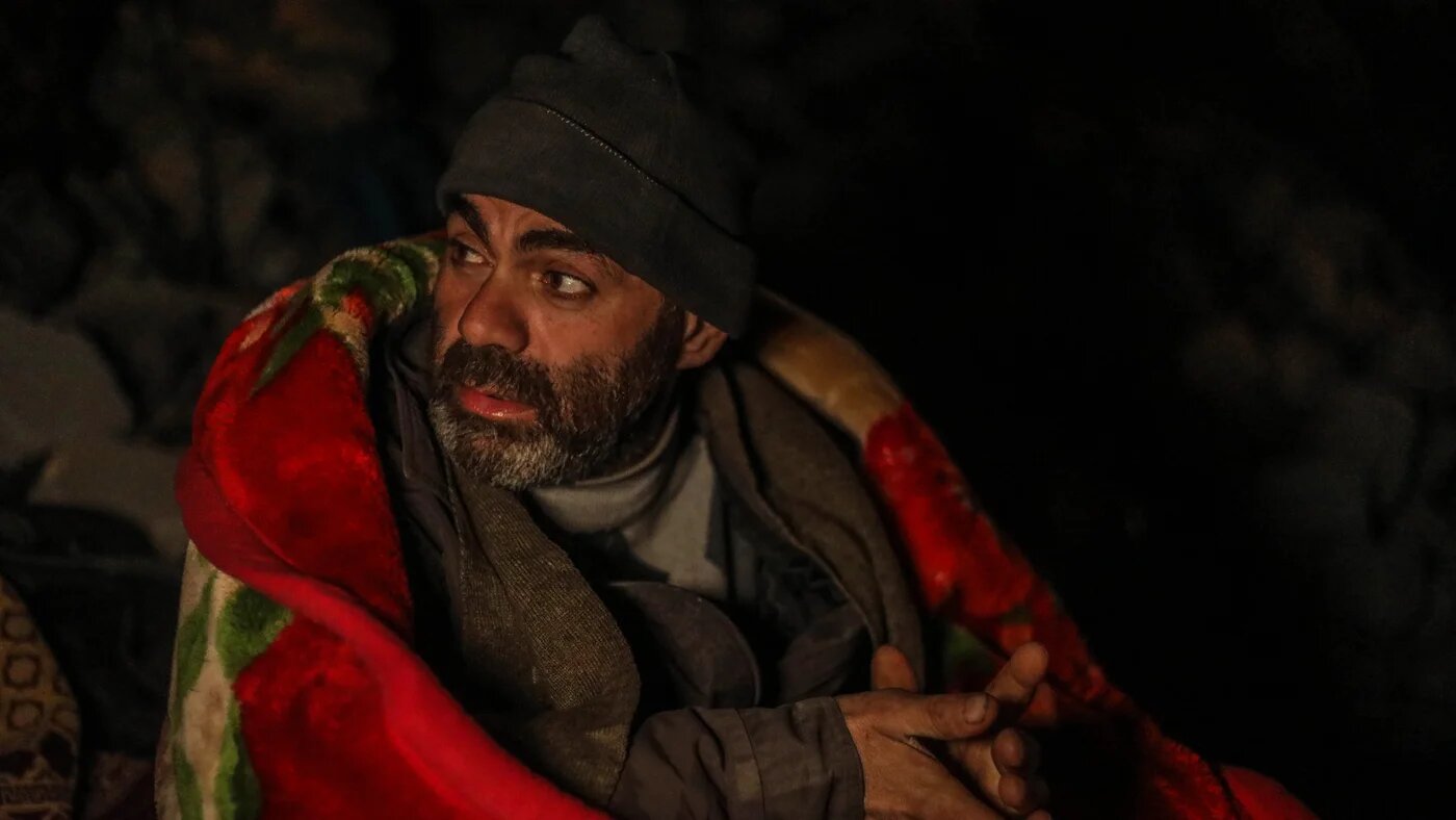 Sami Jaqir waiting for news about his family outside their flattened home in Jaqir townm Syria on 9 February 2023 (MEE/Izzeddin Kasim)