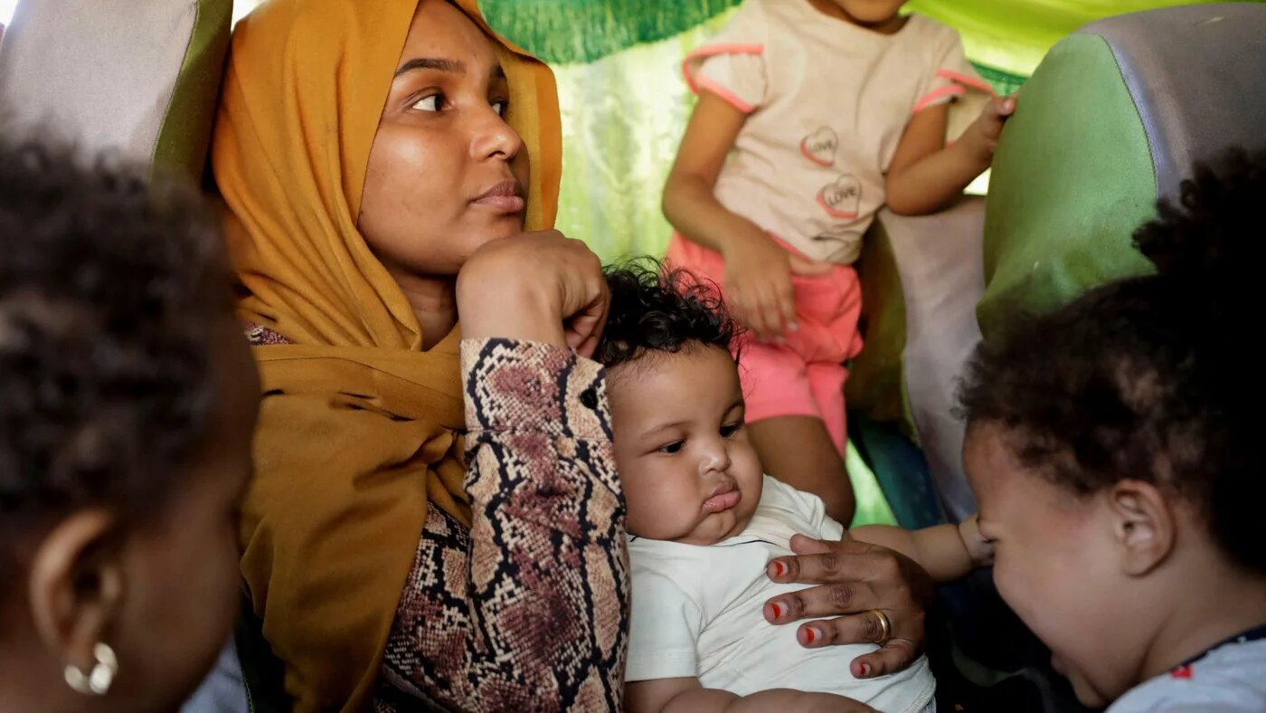 A family sits in a bus as passengers fleeing from Sudan arrive at the Argeen land port, after being evacuated from Khartoum on 28 April (Reuters)