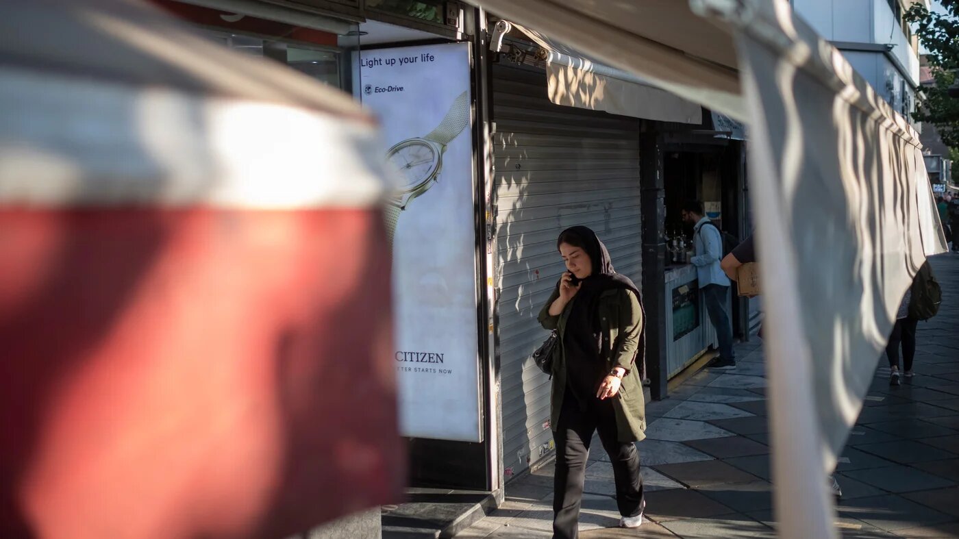An Iranian woman walks along an avenue in downtown Tehran while speaking on her cell phone, 12 September  2023 (Reuters)