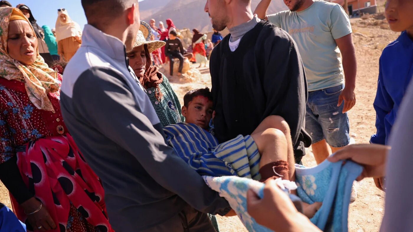 A boy who was injured when a part of a wall fell on his leg is carried by neighbours waiting for an ambulance in the aftermath of a earthquake, in Ighil 11 September (Reuters)