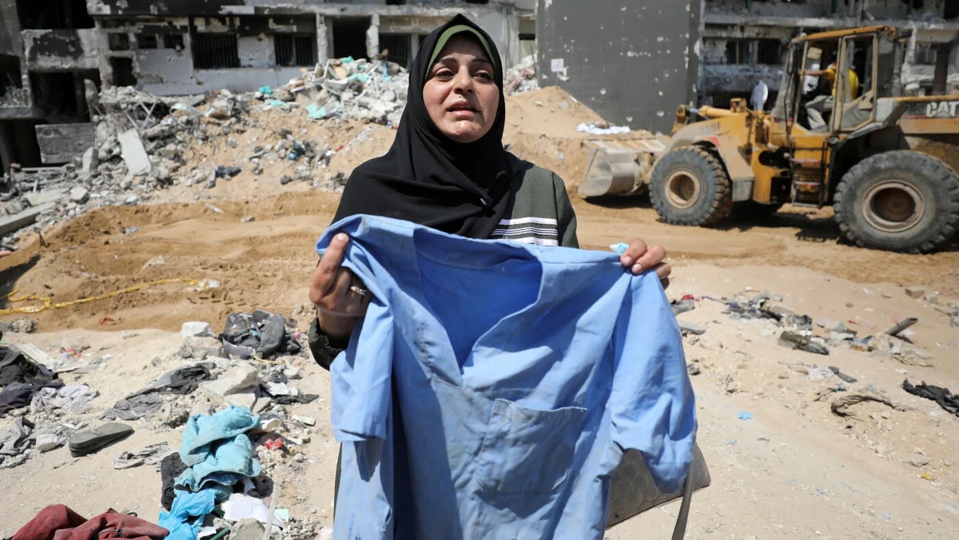 A woman holds doctors scrubs on 8 April 2024 as rescuers searched for dead bodies inside Gaza City's al-Shifa Hospital after Israeli forces destroyed it (Reuters/Dawoud Abu Alkas)