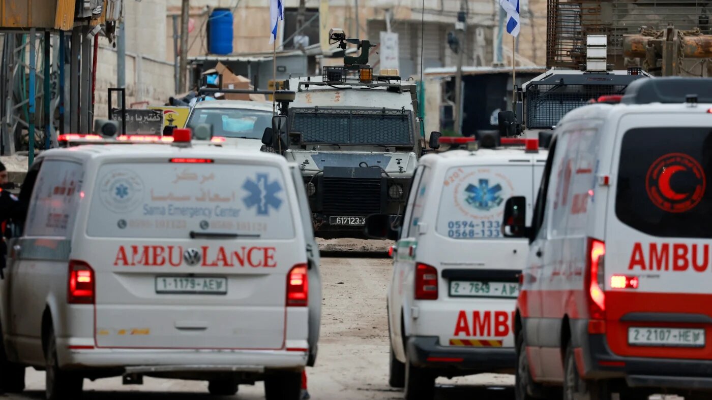An Israeli military vehicle blocks Palestinian ambulances in the occupied West Bank city of Jenin on 22 January 2025 (Reuters/Ammar Awad)