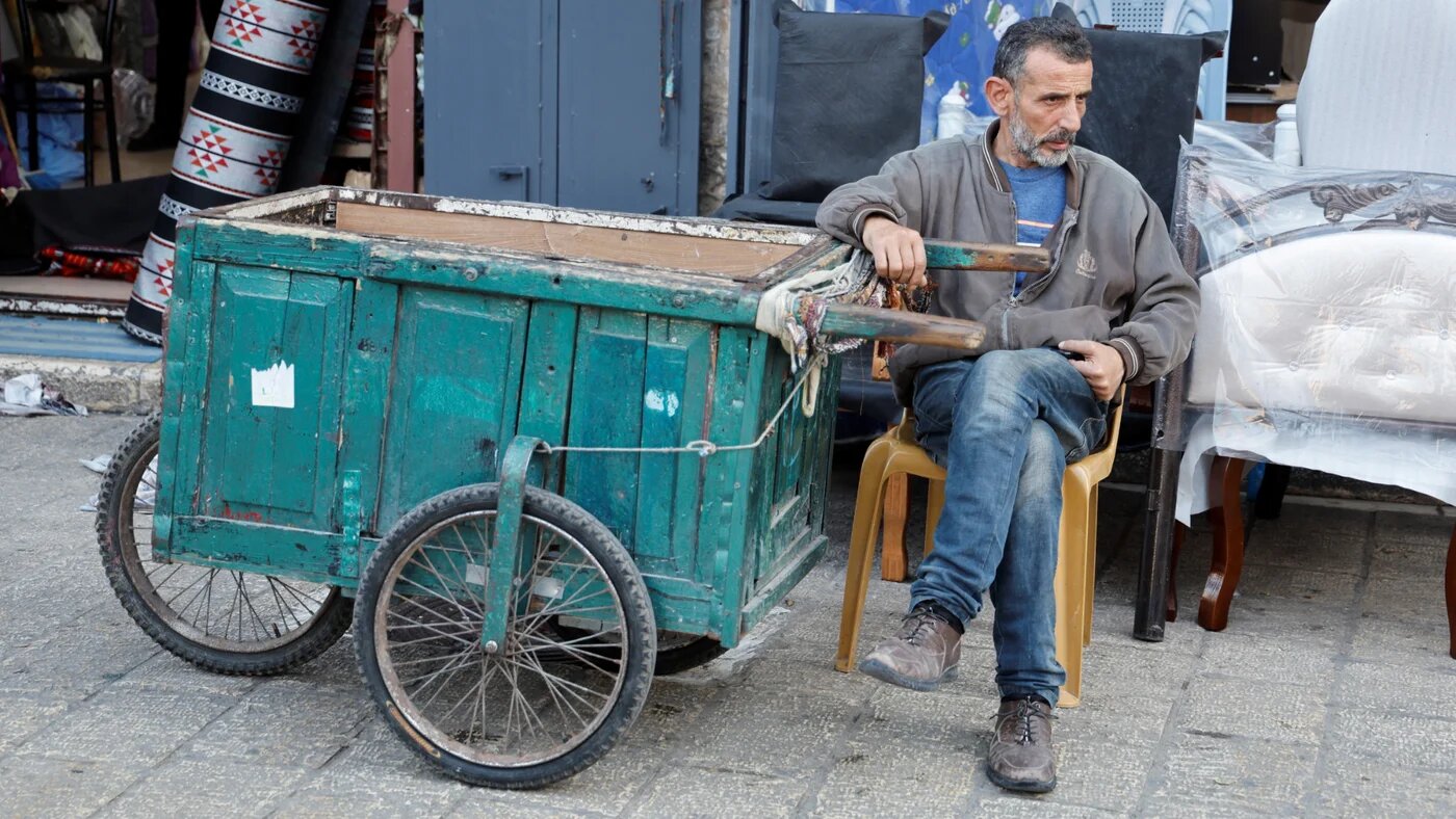 A man sits at the Nablus market, as the region's market and economy are facing difficulties due to Israeli military restrictions in the occupied West Bank, 15 March 2025 (Reuters/Raneen Sawafta)