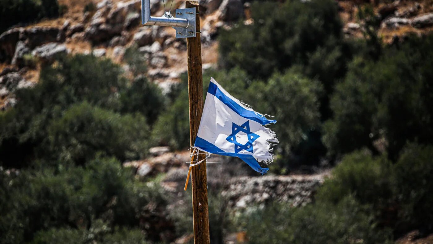 An Israeli flag hangs in a Palestinian neighbourhood in Bruqin, west of Nablus in the occupied West Bank, on 28 July 2025, after settlers launched flag campaigns in Palestinian towns following the Israeli parliament's annexation vote (Nasser Ishtayeh/SOPA Images via Reuters Connect)